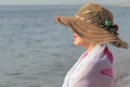 Middle-aged woman in a straw hat against the background of the sea
