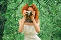 Female portrait. Red-haired girl in a lace dress takes pictures, holding a retro camera in her hands Royalty Free Stock Photo