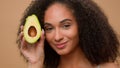 Female portrait studio background smiling African American woman holding fresh healthy avocado face beauty skin care Royalty Free Stock Photo