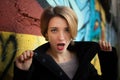 Female portrait of young girl with short blonde hair near the wall with graffiti. Youth culture, street art concept Royalty Free Stock Photo