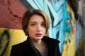 Female portrait of young girl with short blonde hair near the wall with graffiti. Youth culture, street art concept Royalty Free Stock Photo