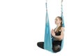 Female posing aerial anti-gravity yoga on hammock. Girl sits in lotus position in blue hammock on white background Royalty Free Stock Photo