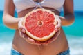 A Woman In A Bikini Is Holding A Grapefruit In Her Hands