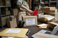 Female post mail storage worker holding tape dispenser sealing shipping box. Royalty Free Stock Photo