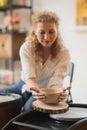 The female potter finished making a clay vase remove it from the potter`s wheel. Creating vase of white clay. Making Royalty Free Stock Photo