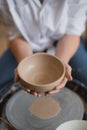 The female potter finished making a clay vase remove it from the potter`s wheel. Creating vase of white clay. Making
