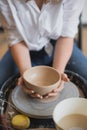 The female potter finished making a clay vase remove it from the potter`s wheel. Creating vase of white clay. Making Royalty Free Stock Photo