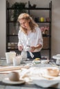 Female potter glazing raw unburned ceramic cup using brush. Earthenware mug putting colorant on pottery workshop. Royalty Free Stock Photo