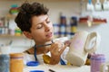 Female potter painting on clay jug in workshop, working in pottery studio. Hobby, small business. Royalty Free Stock Photo