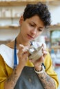 Female potter painting on clay jug in workshop, working in pottery studio. Hobby, small business. Royalty Free Stock Photo