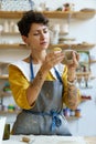 Female potter painting on clay jug in workshop, working in pottery studio. Hobby, small business. Royalty Free Stock Photo