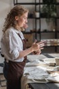 Female potter shaping piece of clay at the table. Woman making ceramic item. Pottery working, handmade and creative Royalty Free Stock Photo