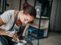 Female potter at work at pottery wheel in workshop, creating bowl from white clay