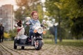 Female preschooler driving electrical motorcycle toy with sidecar and her dog in it, smiling