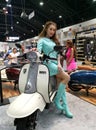 A female presenter sits on a scooter