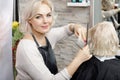 Female pretty smiling hairdresser sitting and cutting the hair Royalty Free Stock Photo