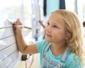 Female Primary Or Elementary School Student Writing On Whiteboard In Classroom Lesson Royalty Free Stock Photo