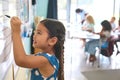 Female Primary Or Elementary School Student Writing On Whiteboard In Classroom Lesson Royalty Free Stock Photo