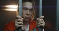 Female prisoner stands in prison cell, holds metal bars by hands