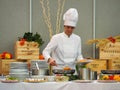 Female professional chef prepares the pasta dish at the buffet for the customer