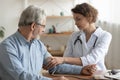 Female doctor measuring senior patient blood pressure at hospital