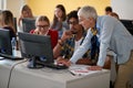 Female professor correcting students errors at an informatics lecture