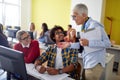 A female professor evaluating work of students at the informatics lecture. Smart young people study at the college. Education, Royalty Free Stock Photo