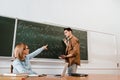 Female professor pointing at chalkboard with equations