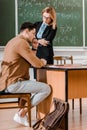 Female professor standing with crossed arms and looking at thoughtful student Royalty Free Stock Photo