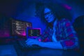 Female programmer coding indoors in a casual workspace with advanced computer setup, surrounded by vibrant lighting Royalty Free Stock Photo