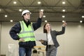 Female project manager in a business suit and white hard hat holds laptop and discusses product details with the chief engineer