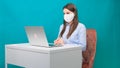 Female in protective mask works on laptop at workplace or at home during a pandemic. The concept of work during