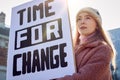 Female Protestor On Demonstration March Holding Time For Change Placard