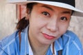 Female protrait in white hat and looking at camera, woman with blue shirt.