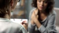 Female psychologist listening to young lady during personal session, depression