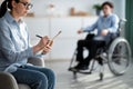 Female psychologist working with handicapped adolescent in wheelchair at office, copy space Royalty Free Stock Photo