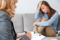 Female psychologyst therapy session with client indoors sitting fulfilling medical form