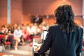 Female public speaker giving talk at Business Event.