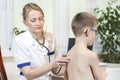 Female pulmonologist doctor during the medical examination. She listens to the boy`s lungs with a stethoscope in the doctor`s offi Royalty Free Stock Photo