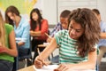 Female Pupil Studying At Desk In Classroom