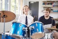 Female Pupil With Teacher Playing Drums In Music Lesson