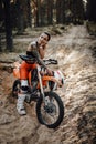 Female racer wearing motocross outfit with semi naked torso sitting on her bike in the forest Royalty Free Stock Photo