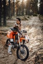 Female racer wearing motocross outfit with semi naked torso sitting on her bike in the forest Royalty Free Stock Photo