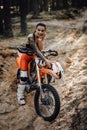 Female racer wearing motocross outfit with semi naked torso sitting on her bike in the forest Royalty Free Stock Photo