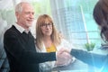 Female realtor giving handshake to happy senior couple after successful agreement  multiple exposure Royalty Free Stock Photo