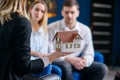 Female realtor, interior designer showing 3d model of house to cute caucasian couple. Royalty Free Stock Photo