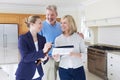 Female Realtor Showing Mature Couple Around House For Sale