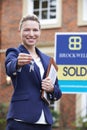 Female Realtor Standing Outside Residential Property Holding Key