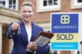 Female Realtor Standing Outside Residential Property Holding Key