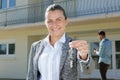 Female realtor standing outside residential property holding keys